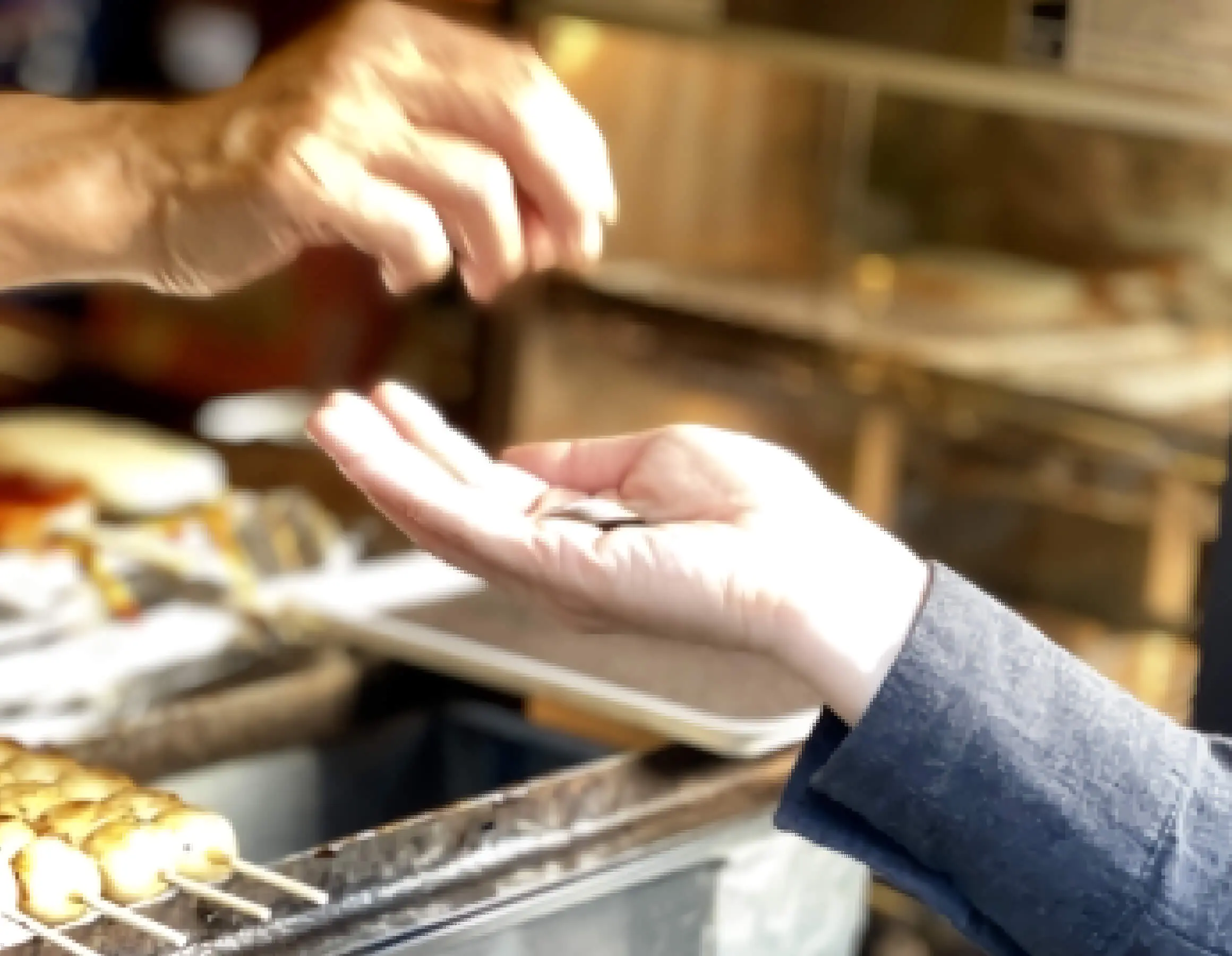 店主がおつりを丁寧に渡している手をアップに写している